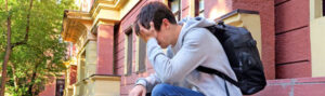 A young man sitting with his head in his hand, appearing stressed or upset.