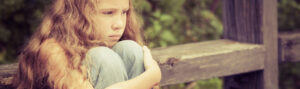 A sad girl sitting alone, hugging her knees thoughtfully.